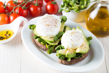 Fototapeta na wymiar Avocado toast, cherry tomato on wooden background. Breakfast with toast avocado, vegetarian food, healthy diet concept. Healthy sandwich with avocado and poached eggs.