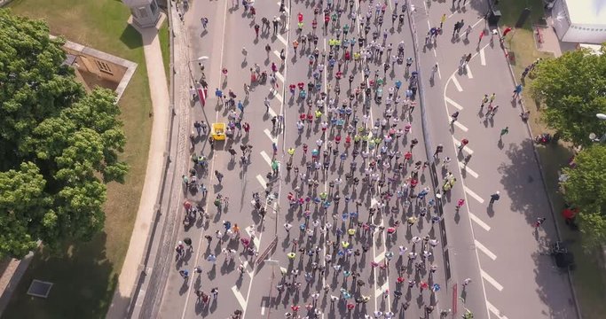 Aerial view from drone on crowd of people who is starting their run on marathon event. Funny shadows on asphalt.
