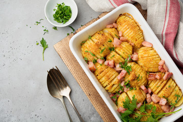 Baked potatoes with ham, herbs and breadcrumbs on gray light background. Scandinavian cuisine. Top view.