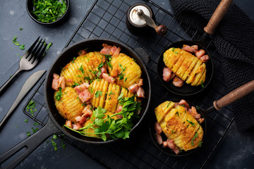 Baked potatoes with ham, herbs and breadcrumbs on dark background. Scandinavian cuisine. Top view.