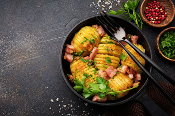 Baked potatoes with ham, herbs and breadcrumbs on dark background. Scandinavian cuisine. Top view.