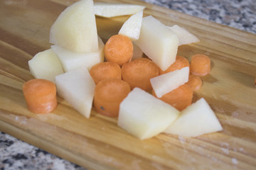 Serving cut carrots and potatoes on a wood chopping board