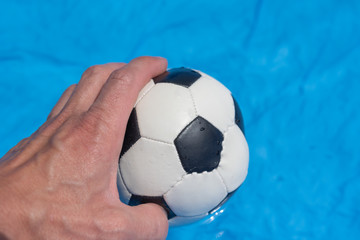 Fototapeta na wymiar Ball in der Hand - Fußball auf blauem Hintergrund