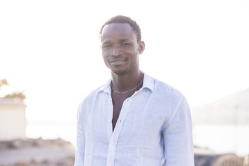 beautiful fashion black race african model man with white shirt and nice face look at the camera. defocused background outdoot location defocused.