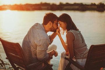 Young couple in love flirting by the river at sunset