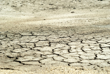 background - cracked dry sun-dried clay crust in a waterless desert half sanded with sand..