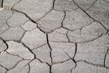 background - cracked dry sun-dried clay crust in a waterless desert half sanded with sand..