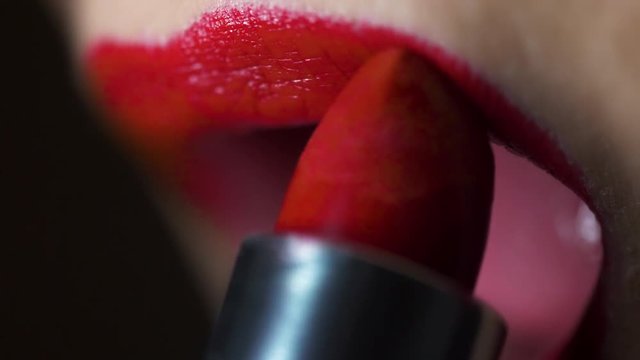 Female Applying Red Lipstick Finish. a slow motion close up view of female lips finishing red lipstick to the lips