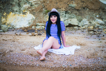 A girl in a striped dress and hat on the beach