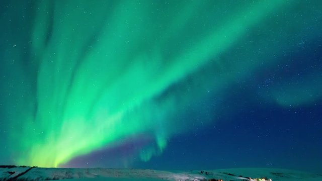 4K Timelapse movement of strong bright Aurora Borealis above the snow covered on the field mountain, northern Iceland