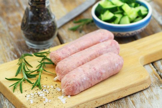 Fresh, raw British pork sausages on wooden board
