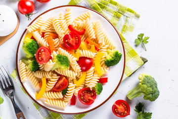 Vegan pasta fusilli with vegetables on white. 
