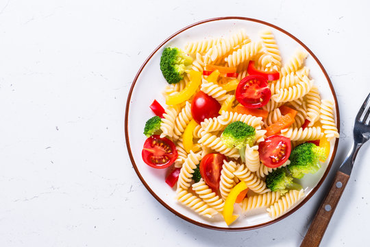 Vegan pasta fusilli with vegetables on white. 