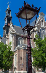 Fototapeta na wymiar Western church Westerkerk and traditional street lamp in the foreground , Amsterdam.