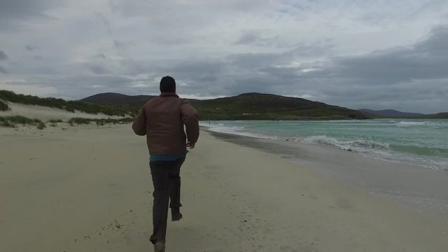 Lonely person running along Seilebost beach on the Isle of Harris, Scotland.