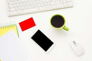 Desktop, keyboard. White smart phone and business card lies on the table,  yellow notebook. White background with copy space, for advertisement, top view