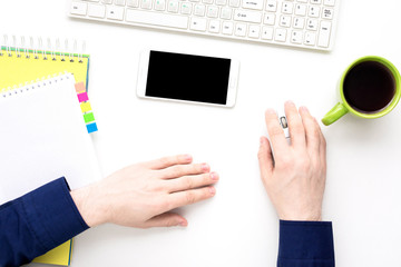 white desk, male hands, guy working at the computer, Cup of coffee, white smart phone lies on the desk,  office supplies,  white background with copy space, for advertisement, top view