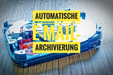 Hard drive 3.5 inches as a data storage with motherboard on a bamboo table and in german Automatische E-Mail-Archivierung in english Automatic e-mail archiving