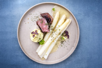Modern barbecue dry aged sliced fillet steak with white asparagus in butter sauce and mashed...
