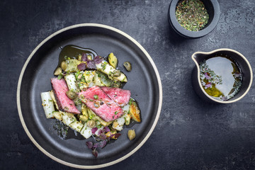 Modern barbecue dry aged sliced fillet steak with asparagus potato salad as top view on a plate