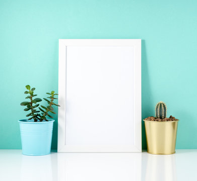 Blank white frame, plant cactus on white table against the blue
