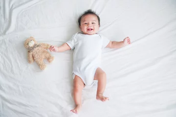 Fototapeten Portrait of a crawling baby on the bed in her room, Adorable baby boy in white sunny bedroom, Newborn child relaxing in bed, Nursery for young children, Textile and bedding for kids © sutthinon602