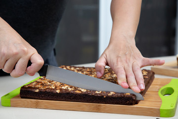 Woman hands using knife to cut brownie cake in to a small pieces