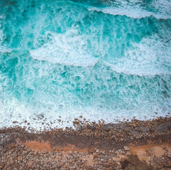 Fototapeta na wymiar Aerial view of ocean waves and brown rocks in the coastline
