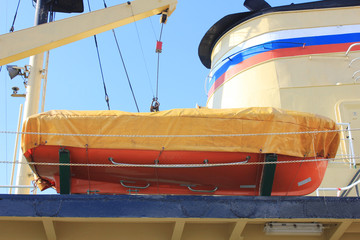 Orange Lifeboat on Russian Naval Ship. View of Lifeboat for Emergency Situationon Deck of Marine Ship. Emergency Evacuation and Life Saving Equipment Onboard Ship