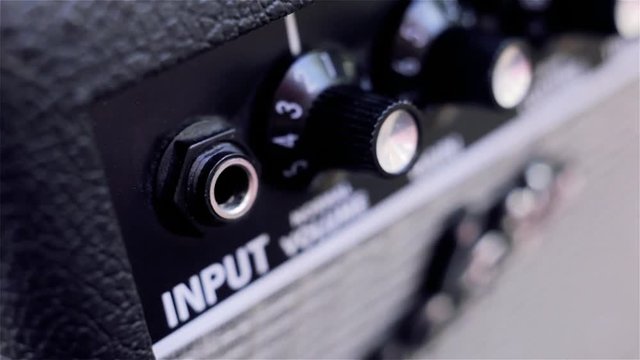 Male Hand Plugging In Jack Cable To Guitar Amplifier. 