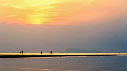 Silhouette of people relaxing on the beach watching the beautiful natural landscape colorful sky and sea during a sunset at Nathon Sunset Viewpoint in Ko Samui, Surat Thani, Thailand, 16:9 widescreen