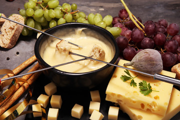 Gourmet Swiss fondue dinner on a winter evening with assorted cheeses on a board alongside a heated pot of cheese fondue
