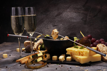 Gourmet Swiss fondue dinner on a winter evening with assorted cheeses on a board alongside a heated pot of cheese fondue