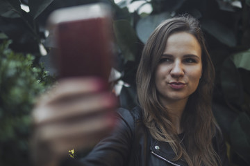 Fototapeta na wymiar Young attractive girl making selfie by mobile phone