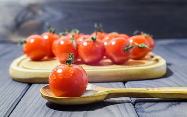 small cherry tomatoes close-up on a dark background in a wooden dish
