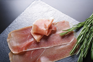 prosciutto jamon ham on a stone background rosemary