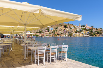 Tables with chairs overlooking sea on Symi island in Greece. © vivoo