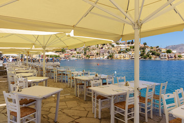 SYMI, GREECE - May 15, 2018: Tables with chairs overlooking sea on Symi island in Greece.