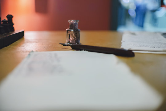 Bottle of ink fountain pen and a piece of paper lie on the table