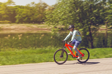 A cyclist in a helmet rides a bicycle path, motion blur