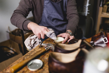 Shoemaker in workshop polishing new handmade beautiful leather shoes.