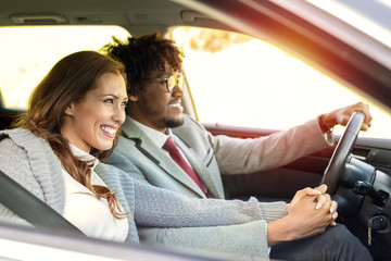 Happy young business couple driving in a car