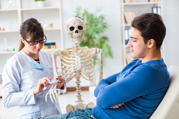 Doctor showing type of injury on skeleton to patient