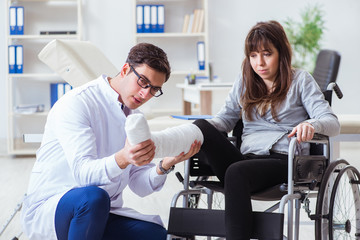 Fototapeta premium Male doctor examining female patient on wheelchair