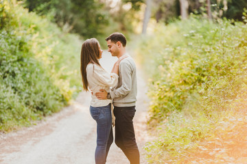 Fototapeta premium Enamored couple hugging and laughing in the middle of the green road