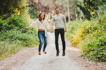 couple jumping and laughing in the middle of the green road