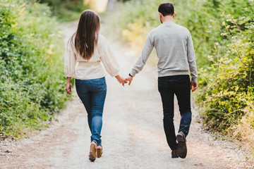 Obraz premium Enamored couple walking and laughing in the middle of the green road