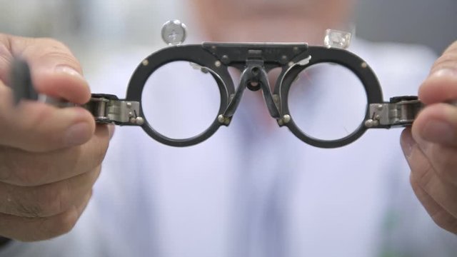 Senior optician giving out Phoropter, POV style. Chinese man using a Phoropter to a patient. Eyecare concept.