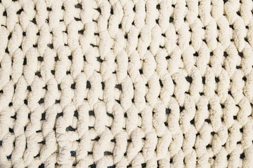 Beige yarn blanket on the bed. Texture background.