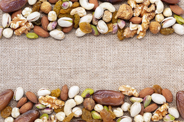 Dried fruits mix and variety of nuts on the brown sackcloth background.